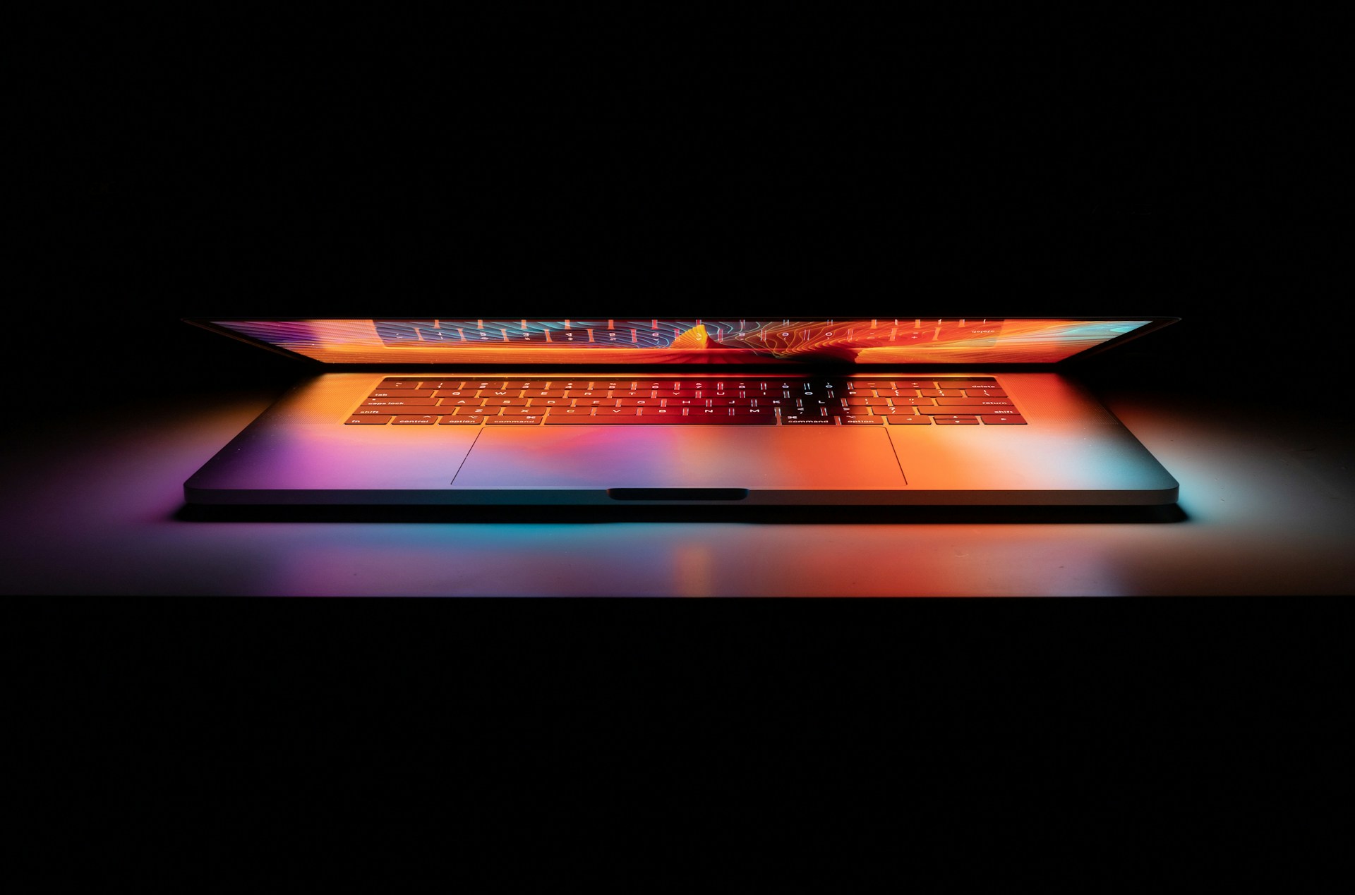 A slightly opened laptop on a dark background with dim lighting.